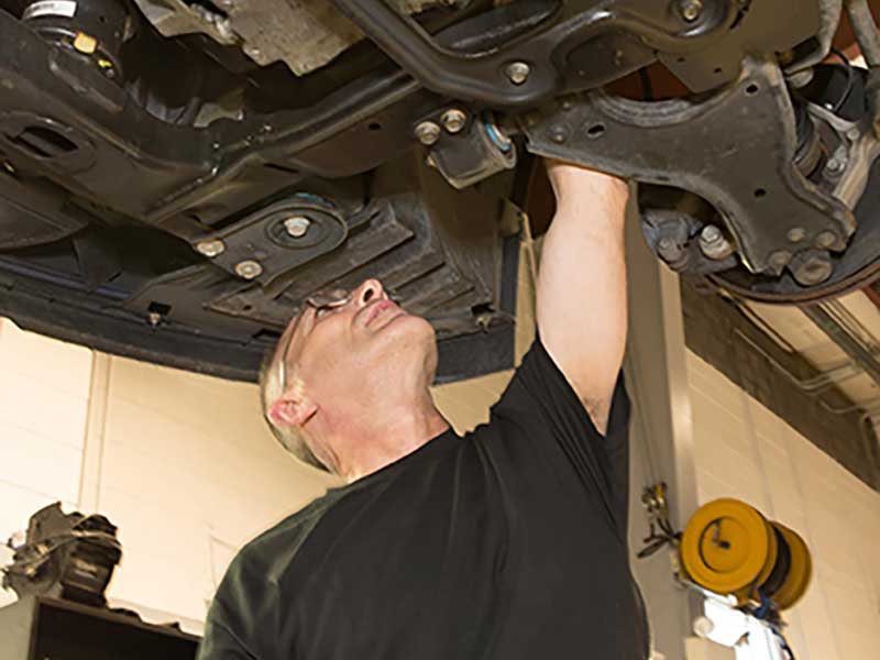 A service tech changing out some parts under a car